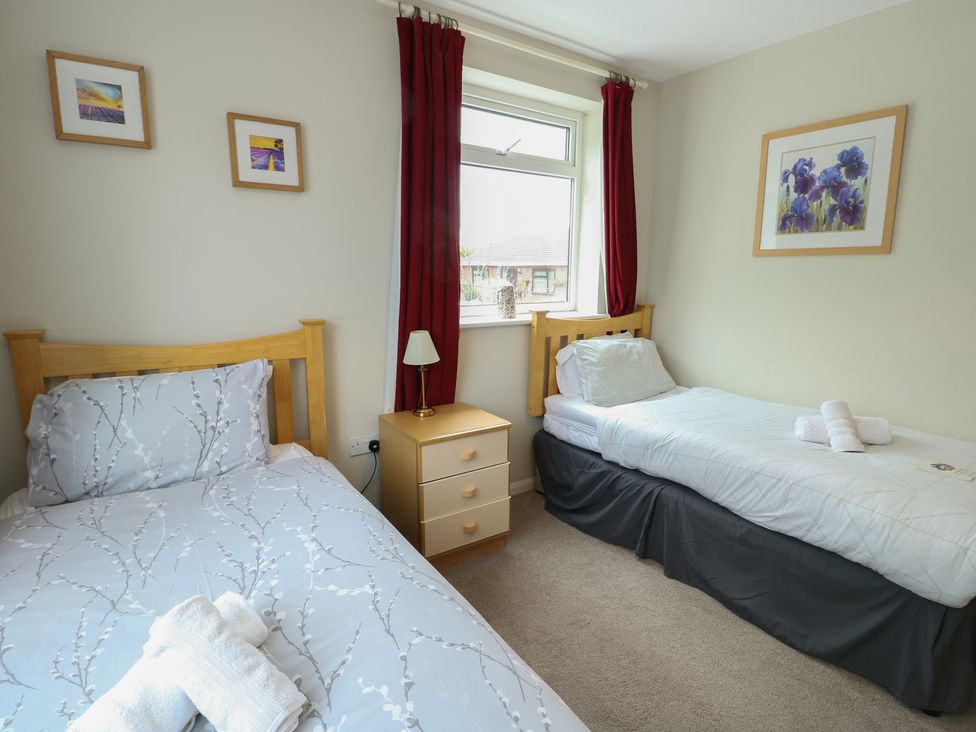 A bedroom with two beds and a window at Awelon in Rhos-On-Sea
