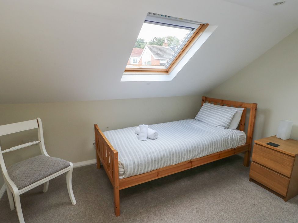 A bedroom with a bed and chair at Awelon Rhos-On-Sea