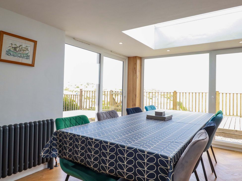 A dining room with a large table covered with a patterned tablecloth and chairs around it at Pink House in Mevagissey