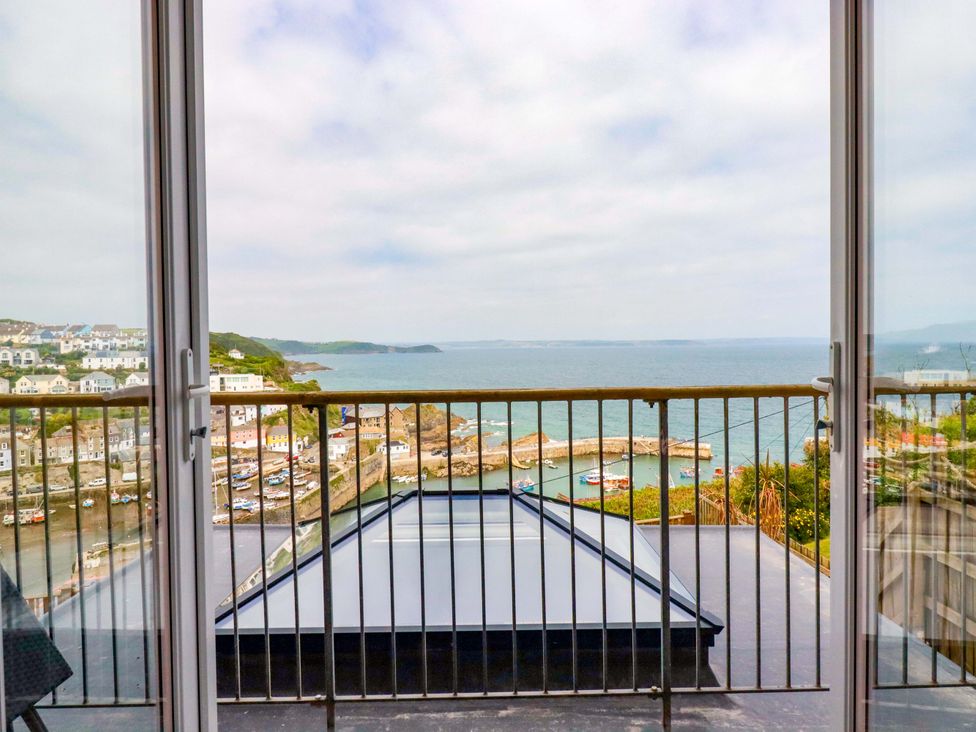 A balcony with metal railing overlooking a coastal town with boats in the harbor at Pink House in Mevagissey