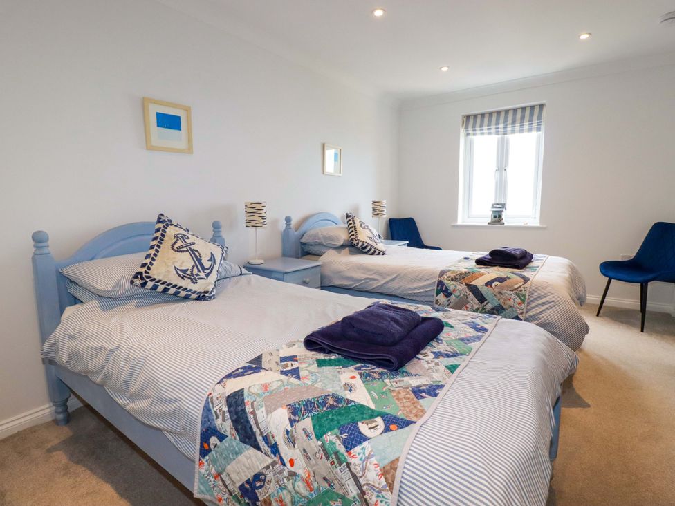 A bedroom with two single beds blue headboards striped bedding patchwork quilts and blue chairs at Pink House in Mevagissey