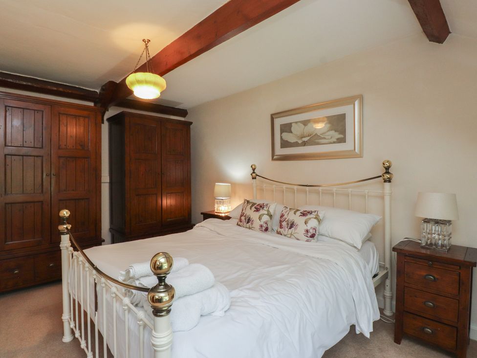A bedroom with a bed and wardrobes at Plas Mawr in Groeslon