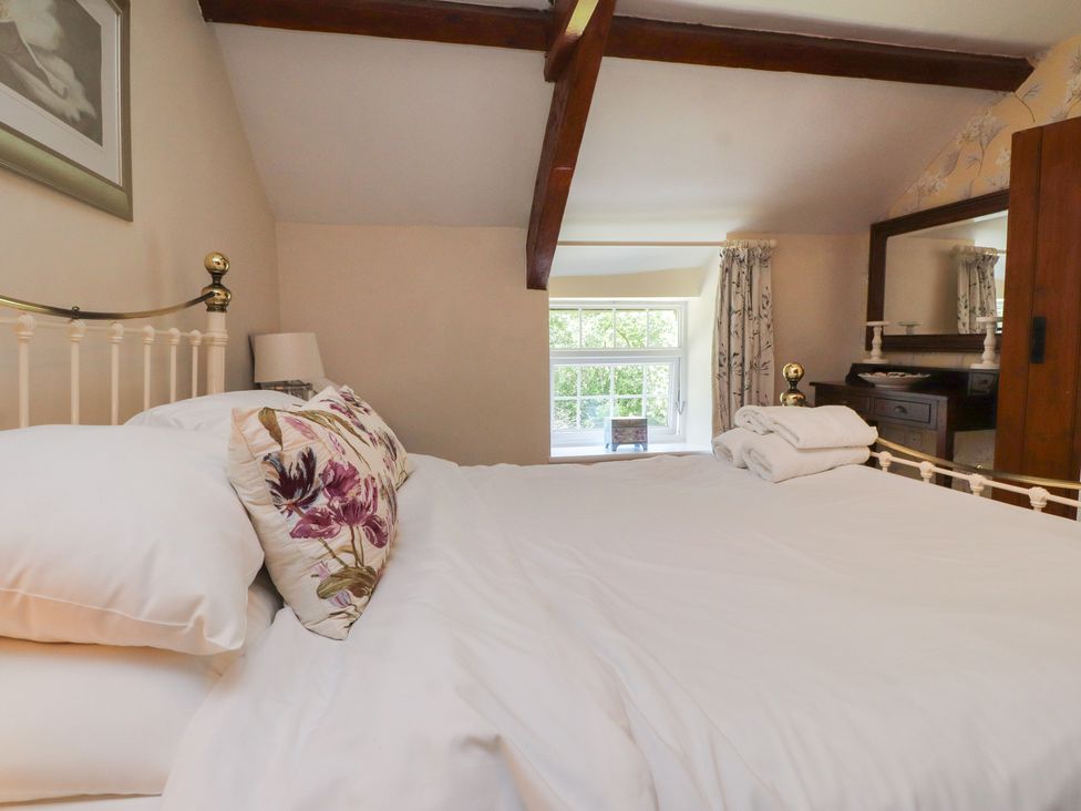 A bedroom with a bed and window at Plas Mawr in Groeslon