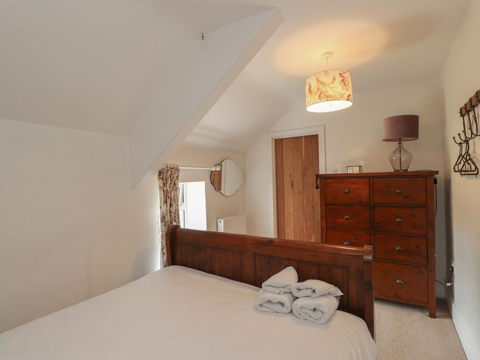 A bedroom with a bed and wooden dresser at Plas Mawr in Groeslon