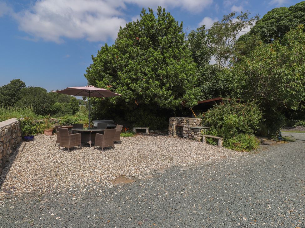 A garden area with a table and chairs under an umbrella at Plas Mawr in Groeslon