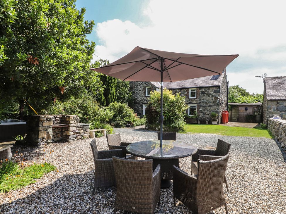 A garden with a table and chairs under an umbrella at Plas Mawr Groeslon
