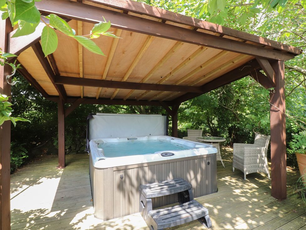 An outdoor area with a hot tub and seating at Plas Mawr Groeslon