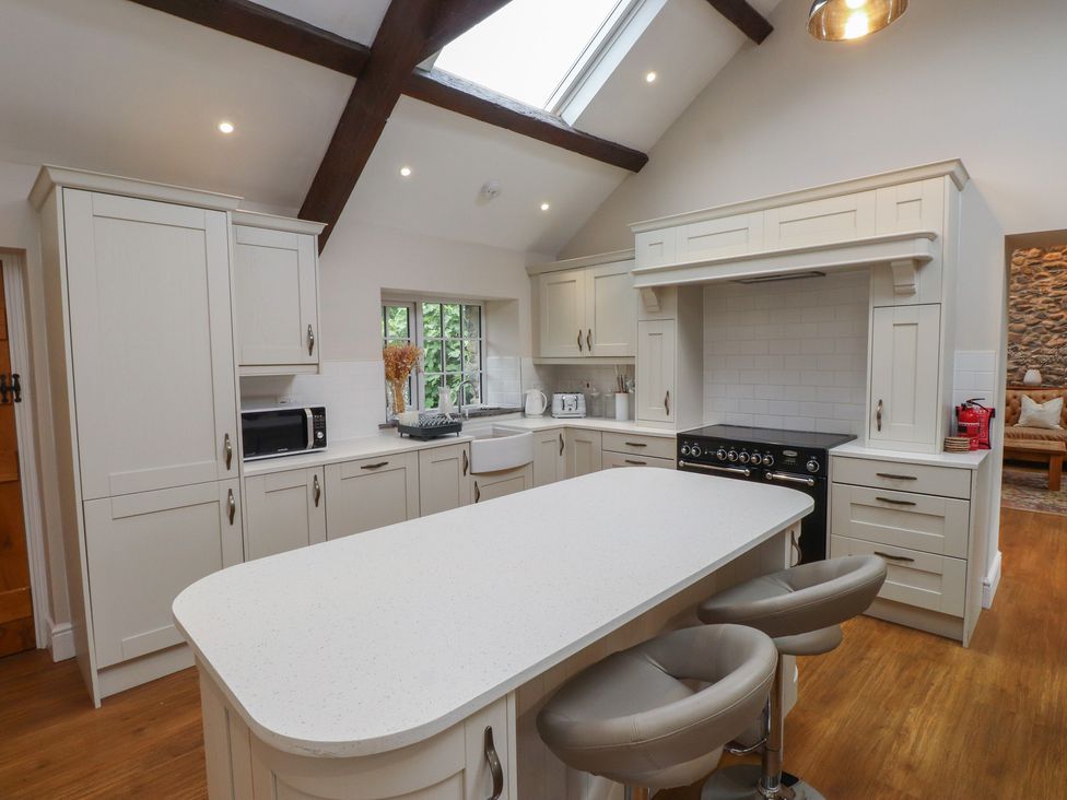 A kitchen with an island, microwave, and sink at Beudy'r Wennol Groeslon
