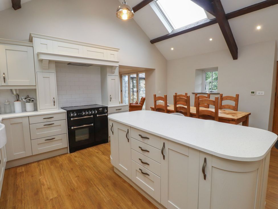 A kitchen with an island and dining table at Beudy'r Wennol Groeslon