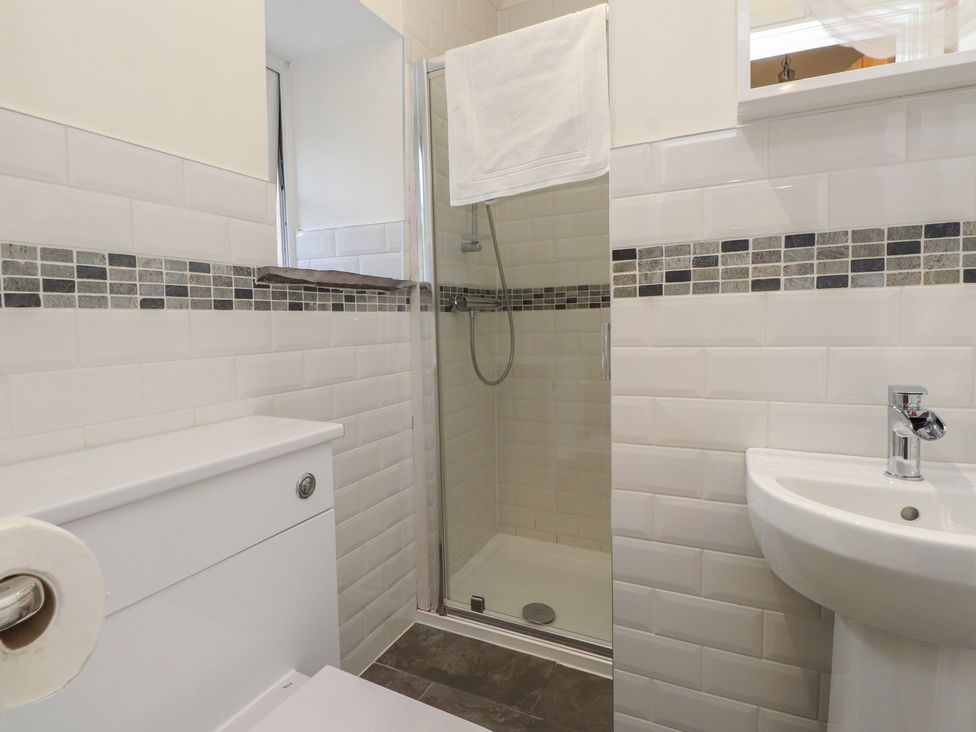 A bathroom with a shower, toilet, and sink at Beudy'r Wennol Groeslon