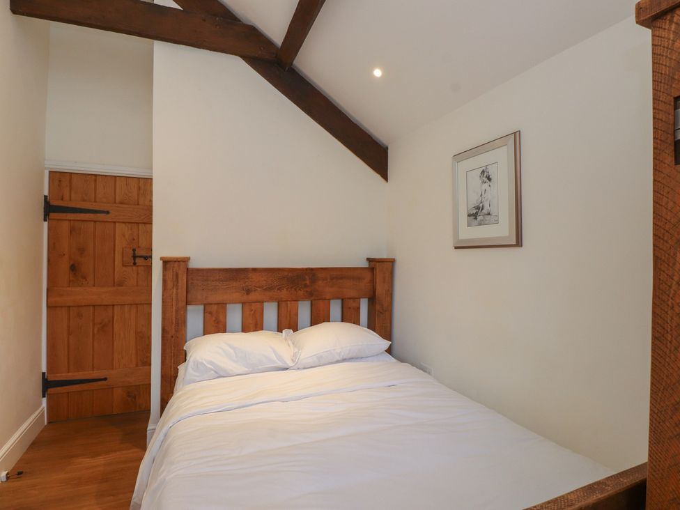 A bedroom with a bed and wooden door at Beudy'r Wennol in Groeslon