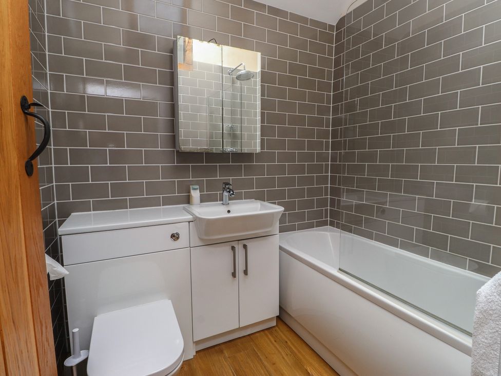 A bathroom with a sink, toilet, and bathtub at Beudy'r Wennol in Groeslon