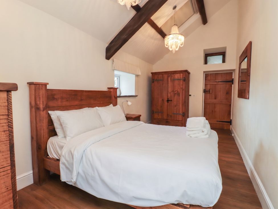 A bedroom with a bed and wooden furniture at Beudy'r Wennol in Groeslon