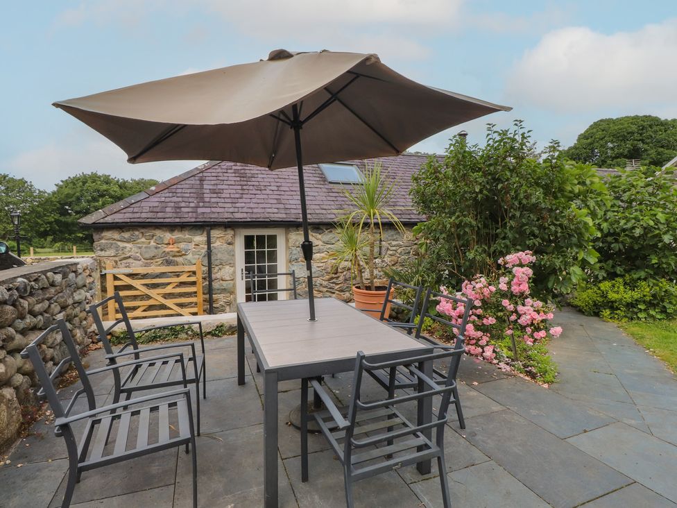 An outdoor seating area with a table and chairs at Beudy'r Wennol Groeslon