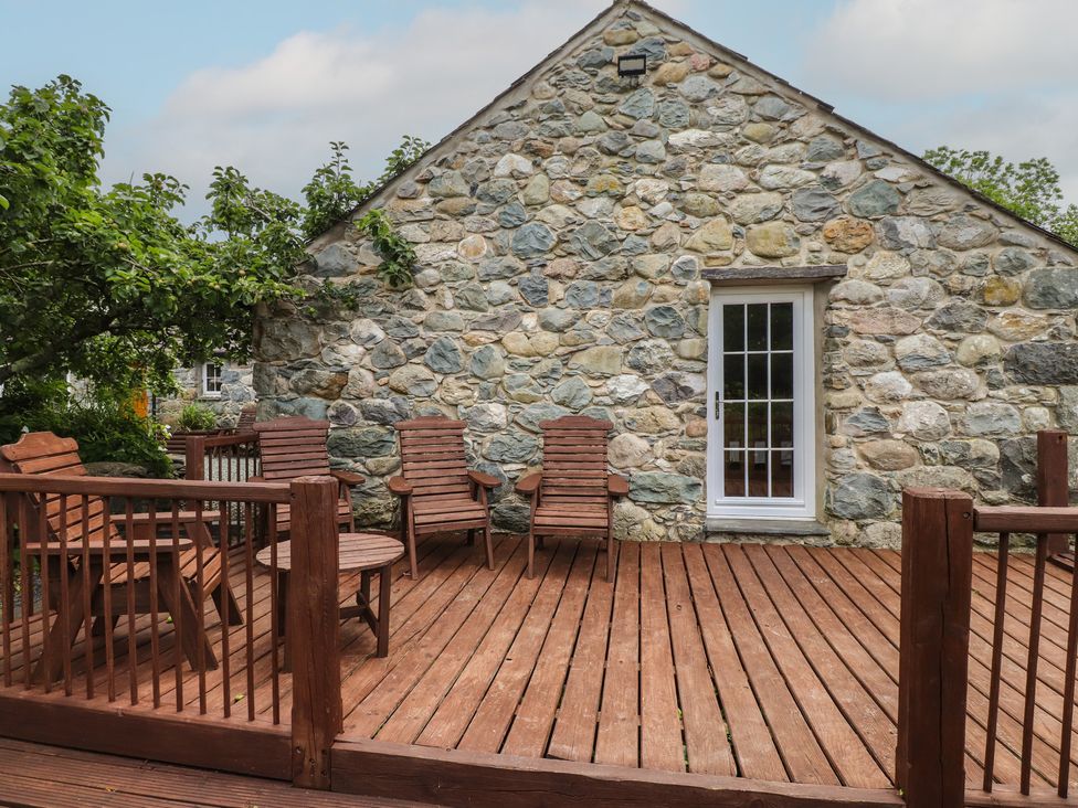 An outdoor area with a wooden deck and chairs at Beudy'r Wennol Groeslon