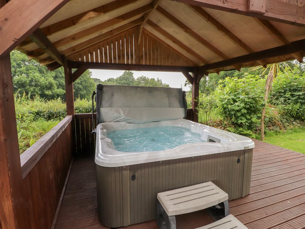 An outdoor area with a hot tub in a wooden gazebo at Beudy'r Wennol in Groeslon