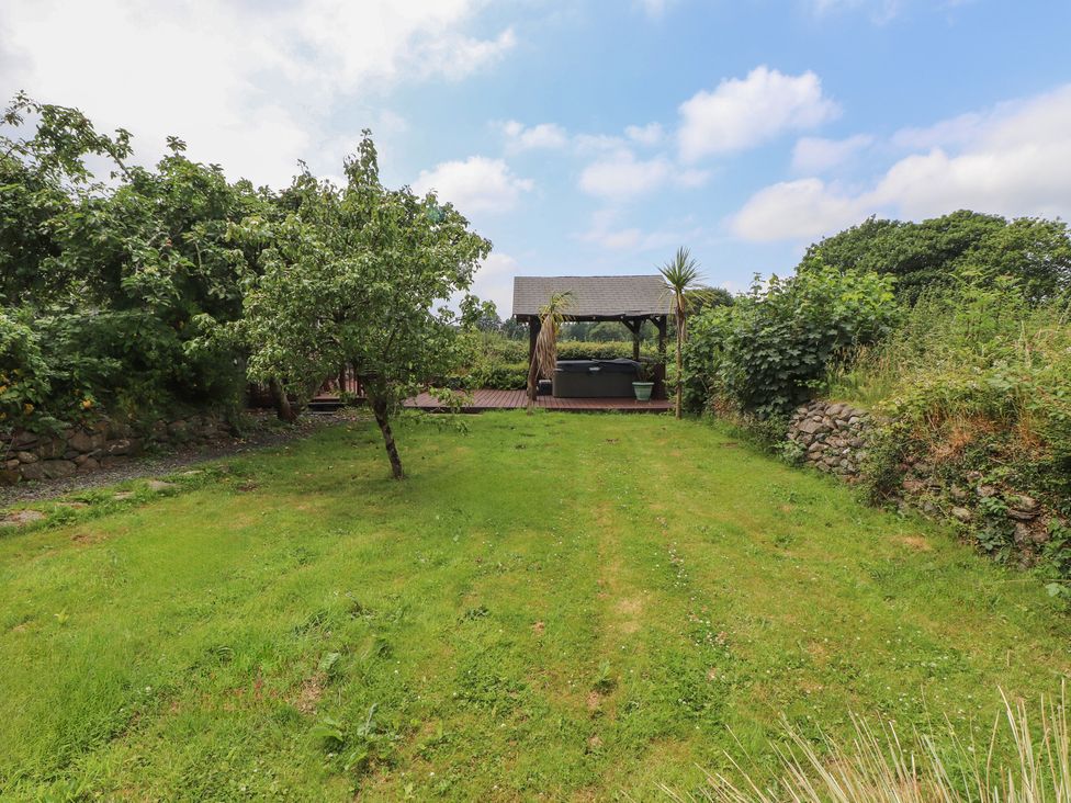 A garden with grass and a gazebo at Beudy'r Wennol in Groeslon