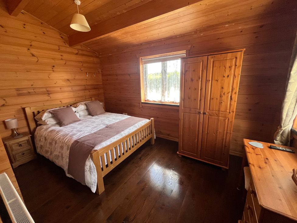 A bedroom with a bed and wardrobe at Holly Lodge in Lanivet near Bodmin