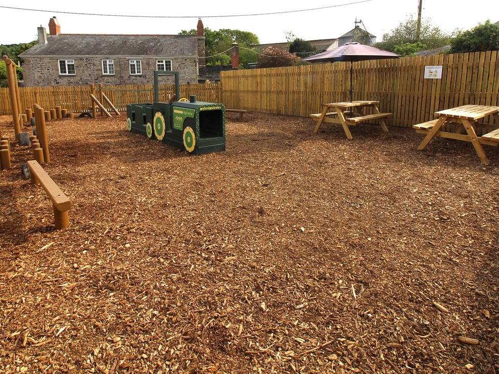 An outdoor play area with wood chips and play equipment at Cherry Lodge, Lanivet near Bodmin