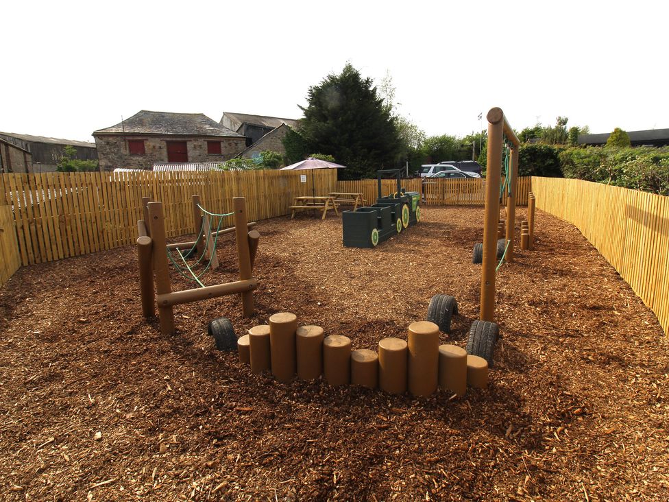 An outdoor play area with swings and climbing frame at Maple Lodge in Lanivet near Bodmin