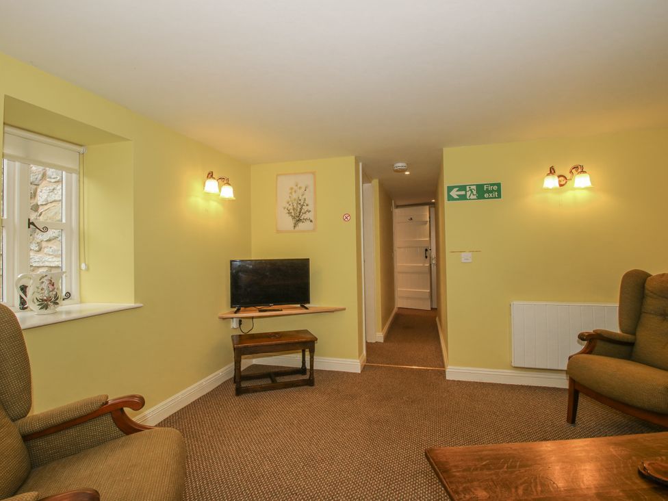 A snug with a television and seating area at Wash House Cottage in Much Wenlock
