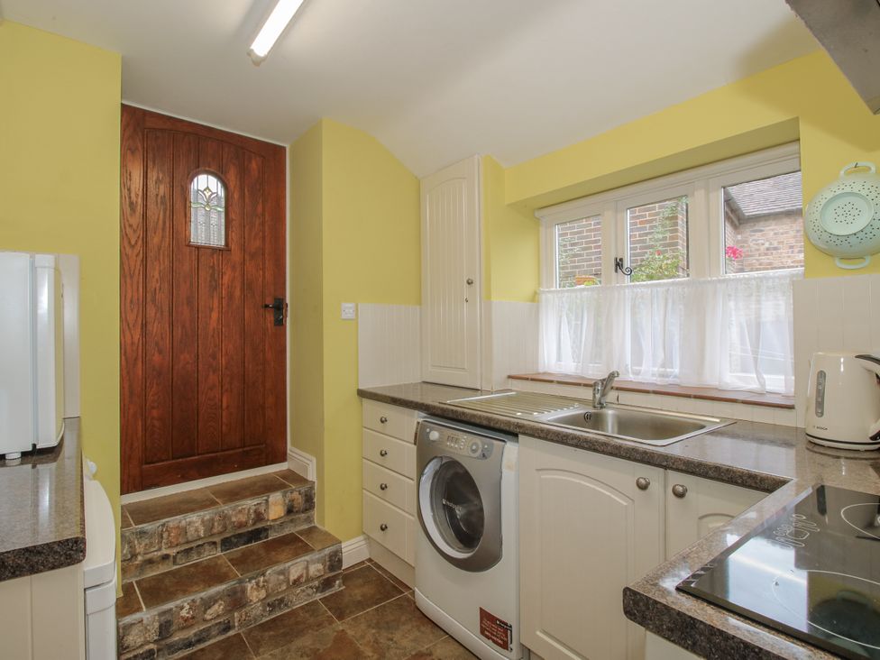 A kitchen with a washing machine and wooden door at Wash House Cottage in Much Wenlock