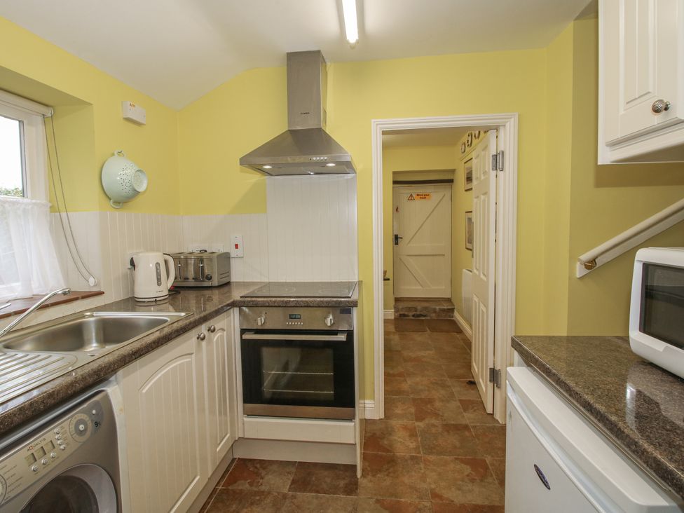 A kitchen with appliances and a door at Wash House Cottage Much Wenlock