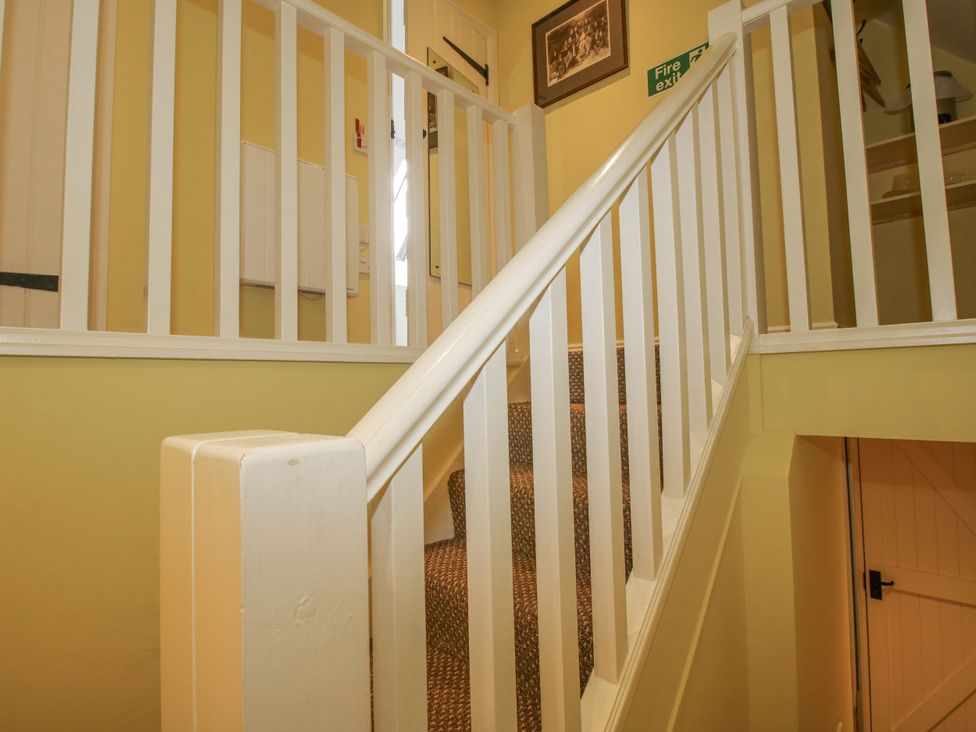 A staircase with a handrail and door at Wash House Cottage Much Wenlock
