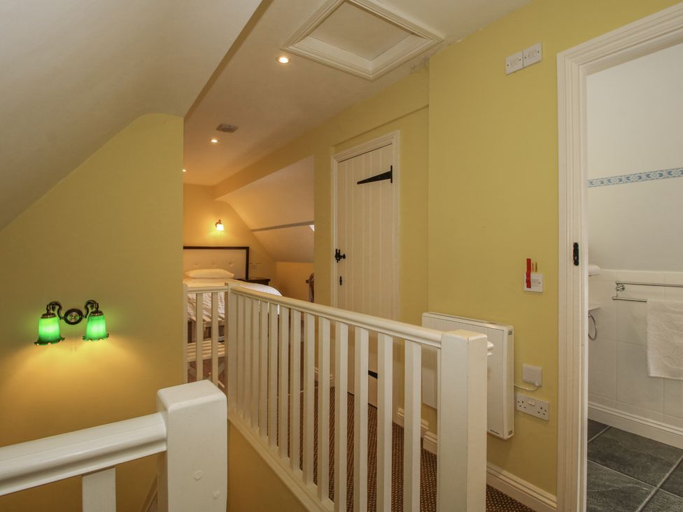A landing with a staircase and doors to a bedroom and bathroom at Wash House Cottage Much Wenlock