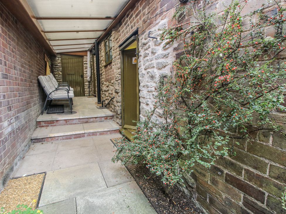 An outdoor area with a chair near a door at Wash House Cottage in Much Wenlock