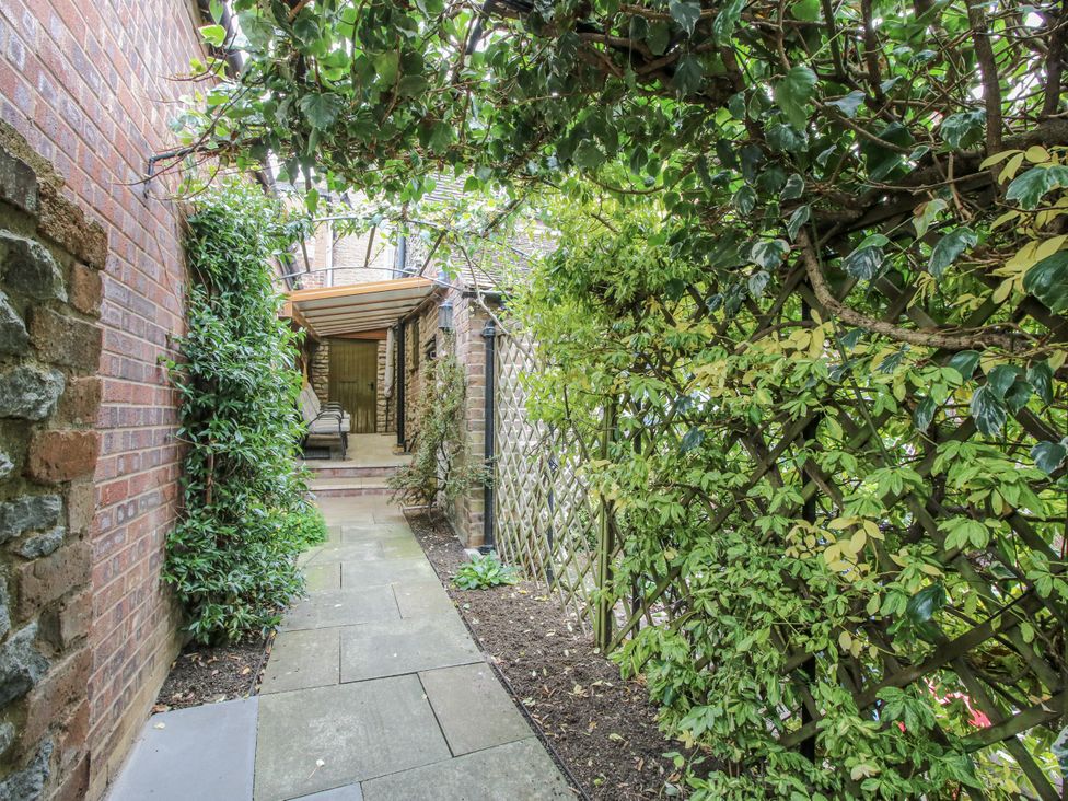 A garden pathway with plants and trellis at Wash House Cottage Much Wenlock
