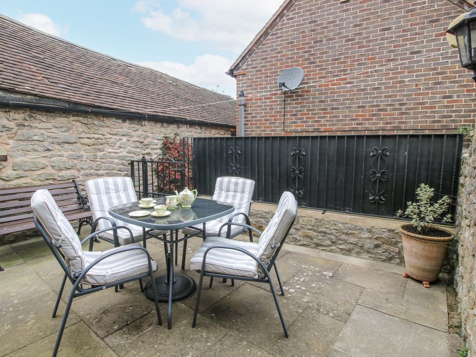 An outdoor seating area with a table and chairs at Wash House Cottage in Much Wenlock