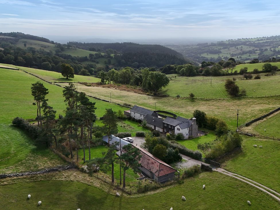 An aerial view of a farmhouse surrounded by fields and trees at Pant Dafydd Goch in Llangollen