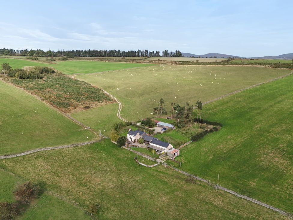 An aerial view of a house surrounded by fields and trees at Pant Dafydd Goch in Llangollen