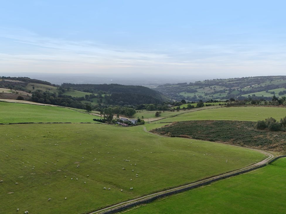 A view of fields and hills with a farmhouse and sheep at Pant Dafydd Goch in Llangollen