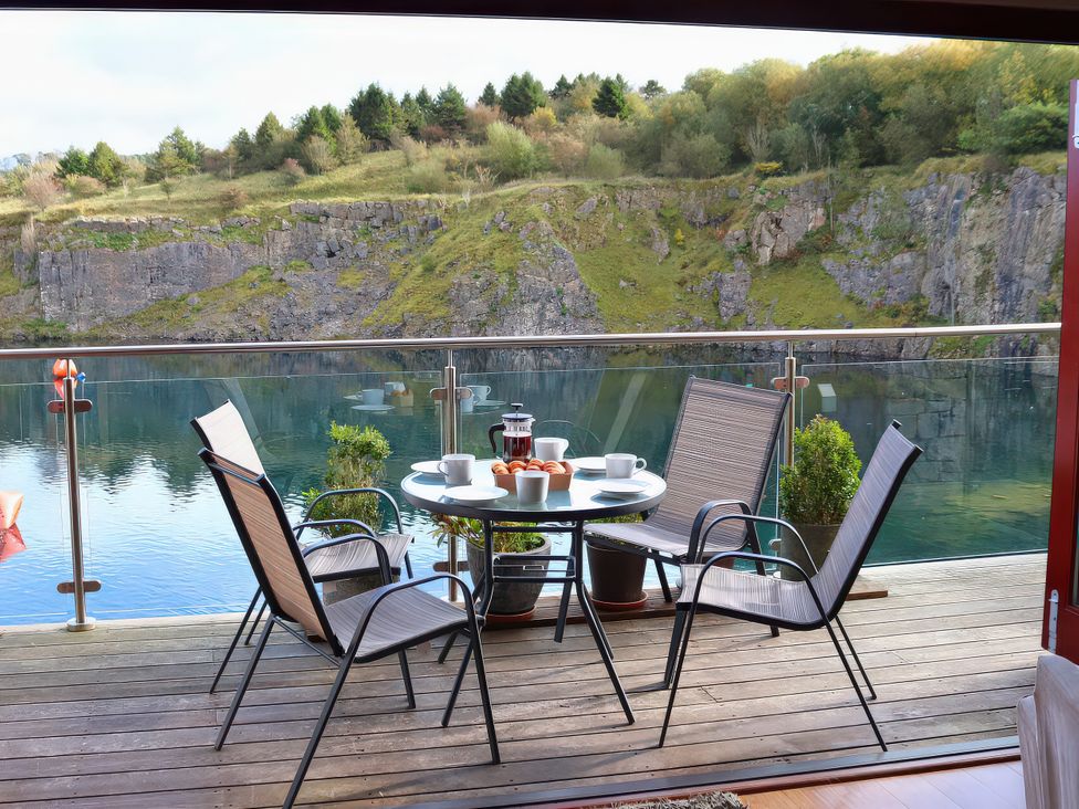 A balcony with a table and chairs overlooking a water body at Boavista in Carnforth