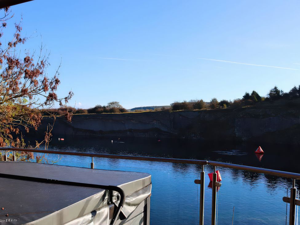 An outdoor view of a lake with cliffs and a hot tub at Boavista in Carnforth