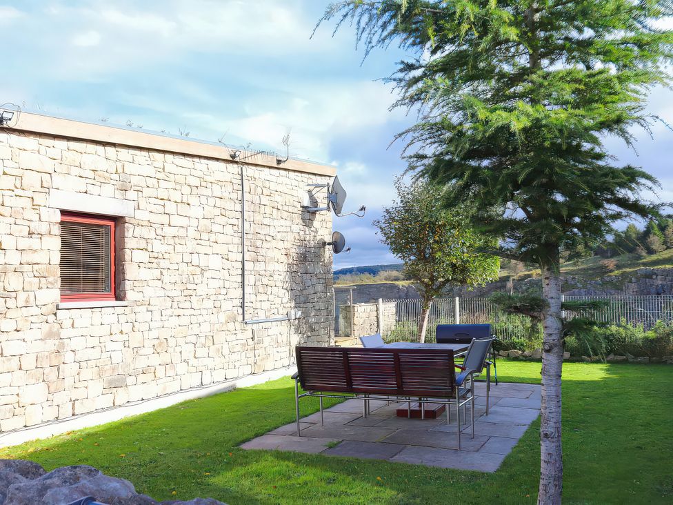 An outdoor area with a stone wall and seating at Boavista in Carnforth