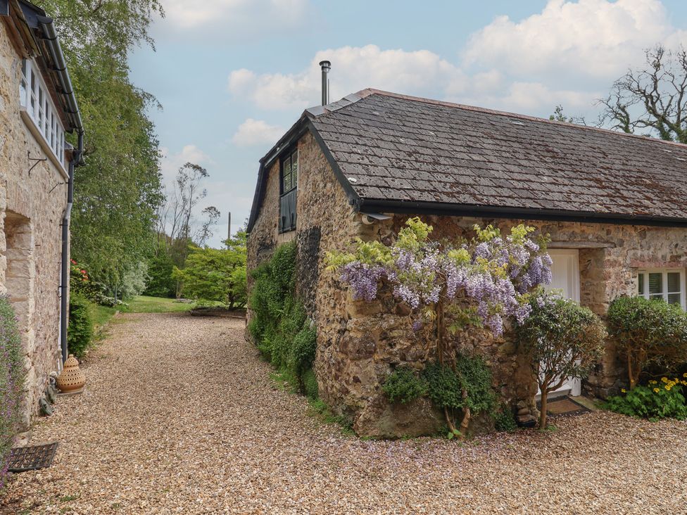A stone cottage with a gravel path and flowers at Pottery Barn in Branscombe