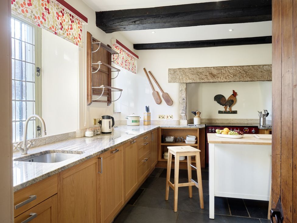 A kitchen with sink, stove, and wooden furniture at Great Bidlake Manor, Bridestowe, near Lydford