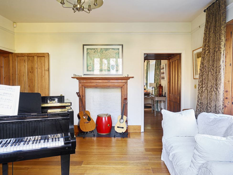 A living room with a piano and guitars at Great Bidlake Manor, Bridestowe, near Lydford