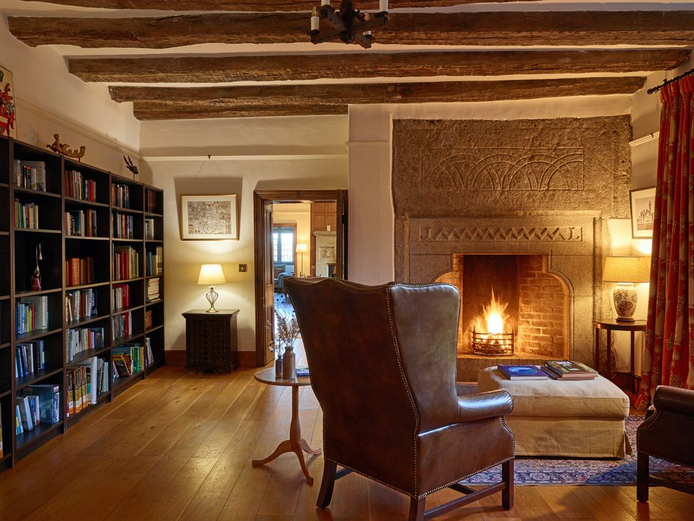A living room with a fireplace and bookshelf at Great Bidlake Manor in Bridestowe, near Lydford