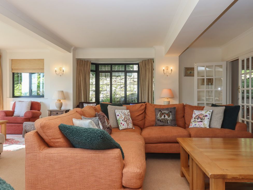 A living room with a large orange sofa and a coffee table at Sandsgate, Spinster's Rock, near Chagford
