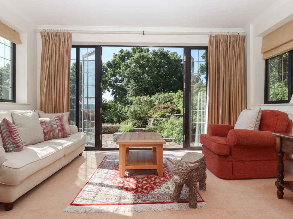 A living room with a couch, table, and chair at Sandsgate, near Chagford