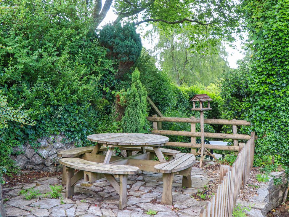 A picnic table with benches in a garden at Little Gate Cottage North Bovey