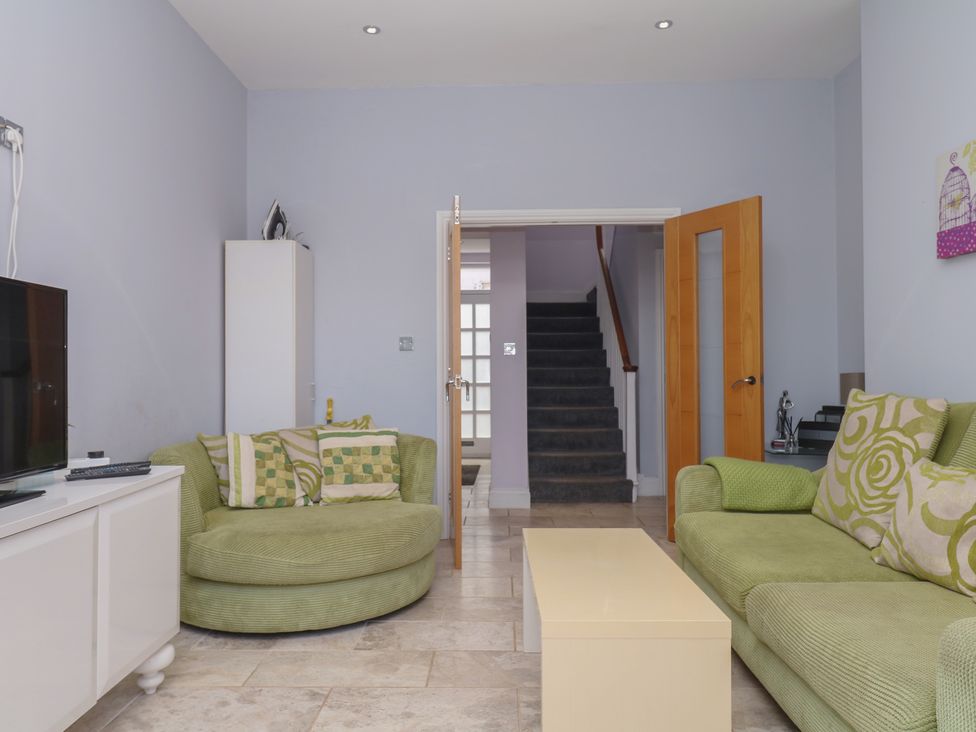 A living room with a television, sofa, and coffee table at The Dolphins in Shaldon