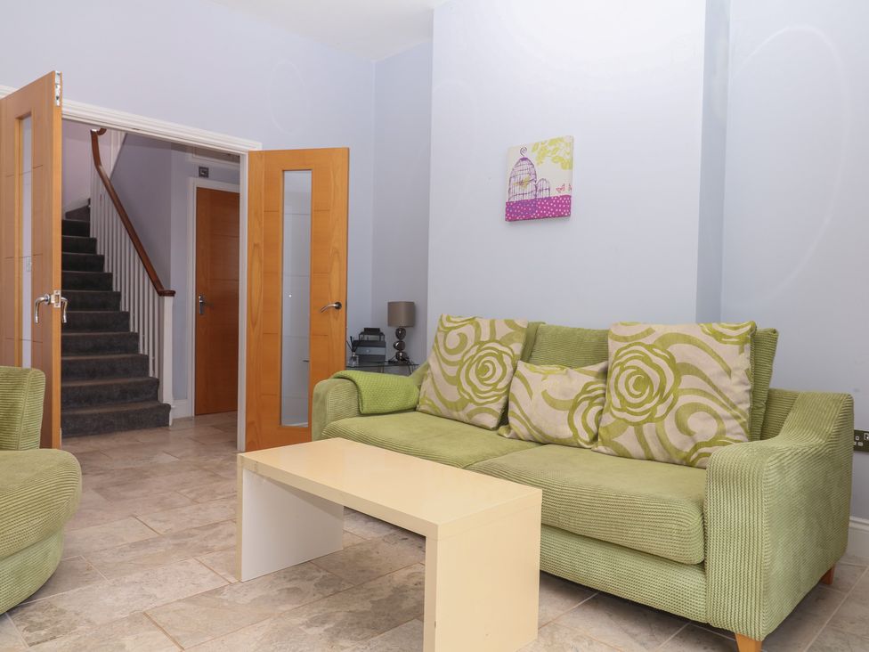 A living room with a green sofa and a small table at The Dolphins in Shaldon