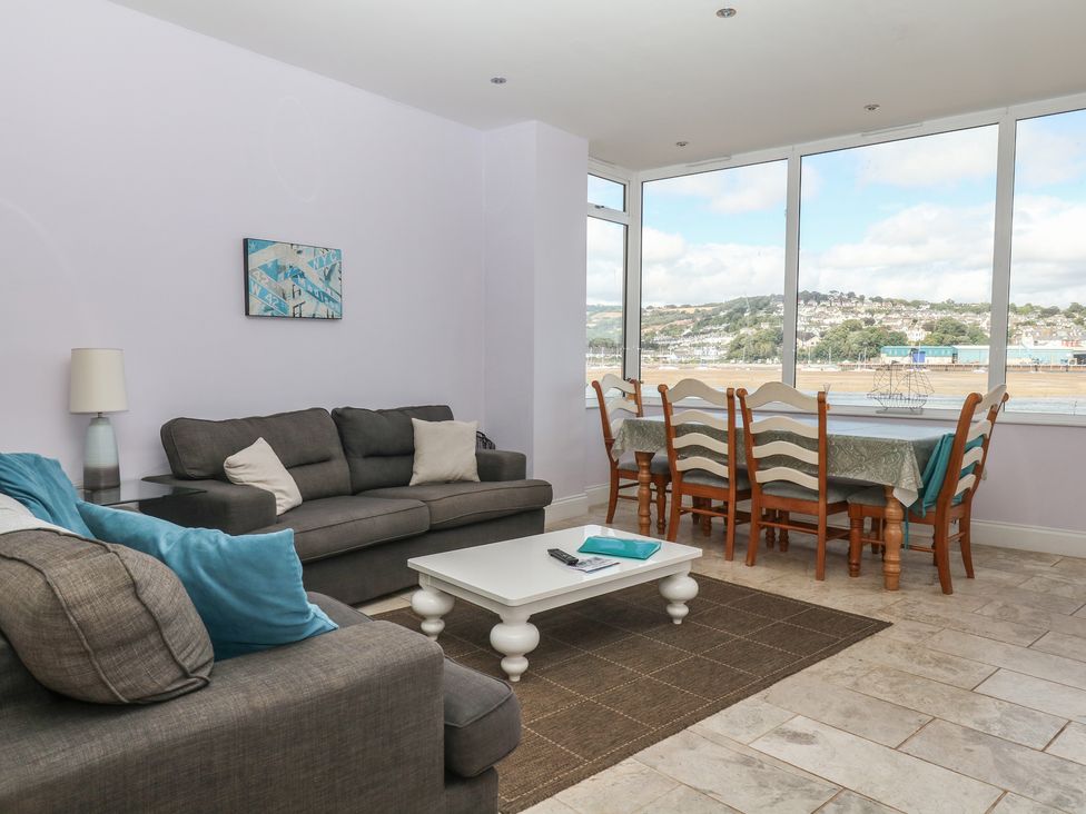 A living room with a sofa and dining table at The Dolphins in Shaldon
