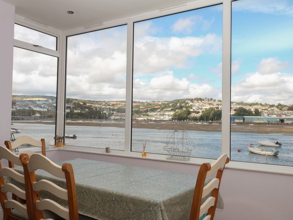 A dining room with a table and chairs overlooking a river at The Dolphins in Shaldon