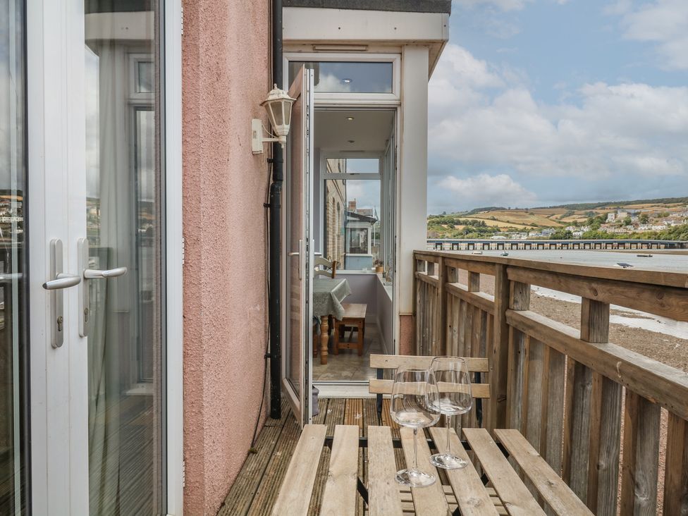 A balcony with a wooden table and glasses at The Dolphins in Shaldon